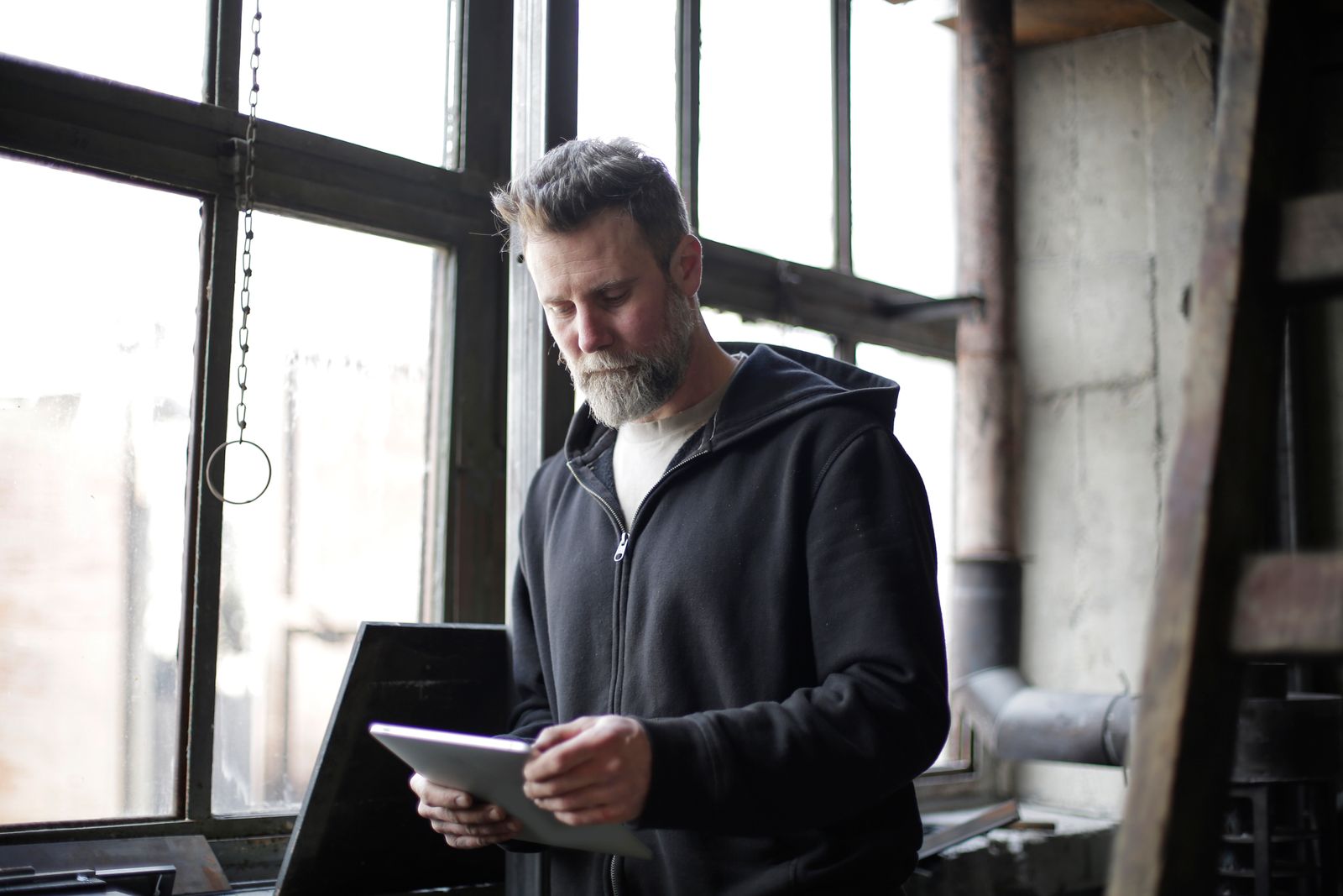 Business owner in his workshop reviewing new customer messages on a tablet