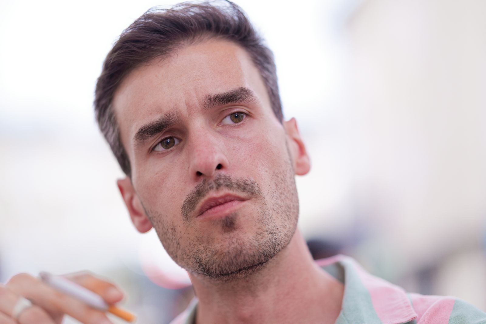 Homme songeur marquant une pause, cigarette en main et cheveux ébouriffés
