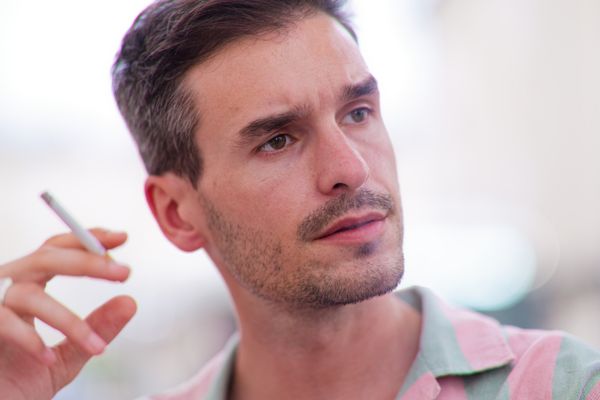 Portrait d'un homme à la cigarette, l'air contemplatif dans un cadre décontracté
