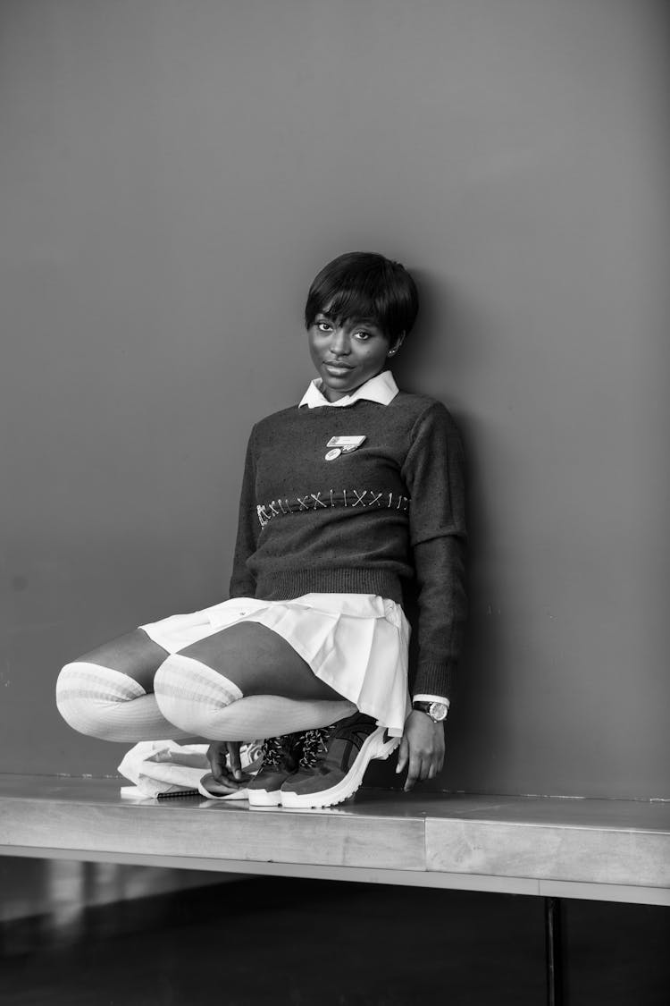 Stylish Ethnic Teen In Short Skirt And Socks Squatting Near Wall