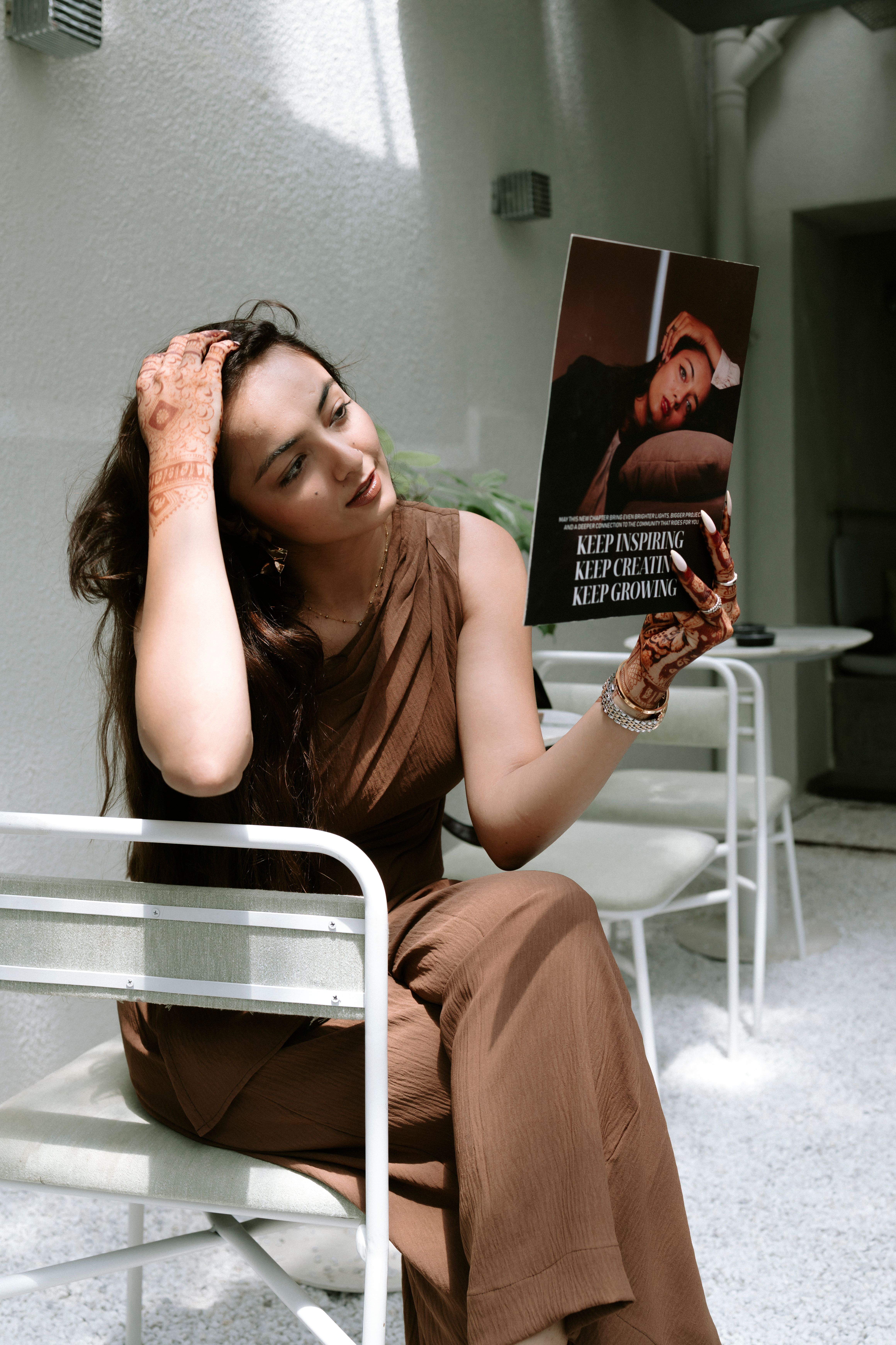 Woman sitting in a sunny cafe reading an inspiring poster. Indoor setting, modern fashion.