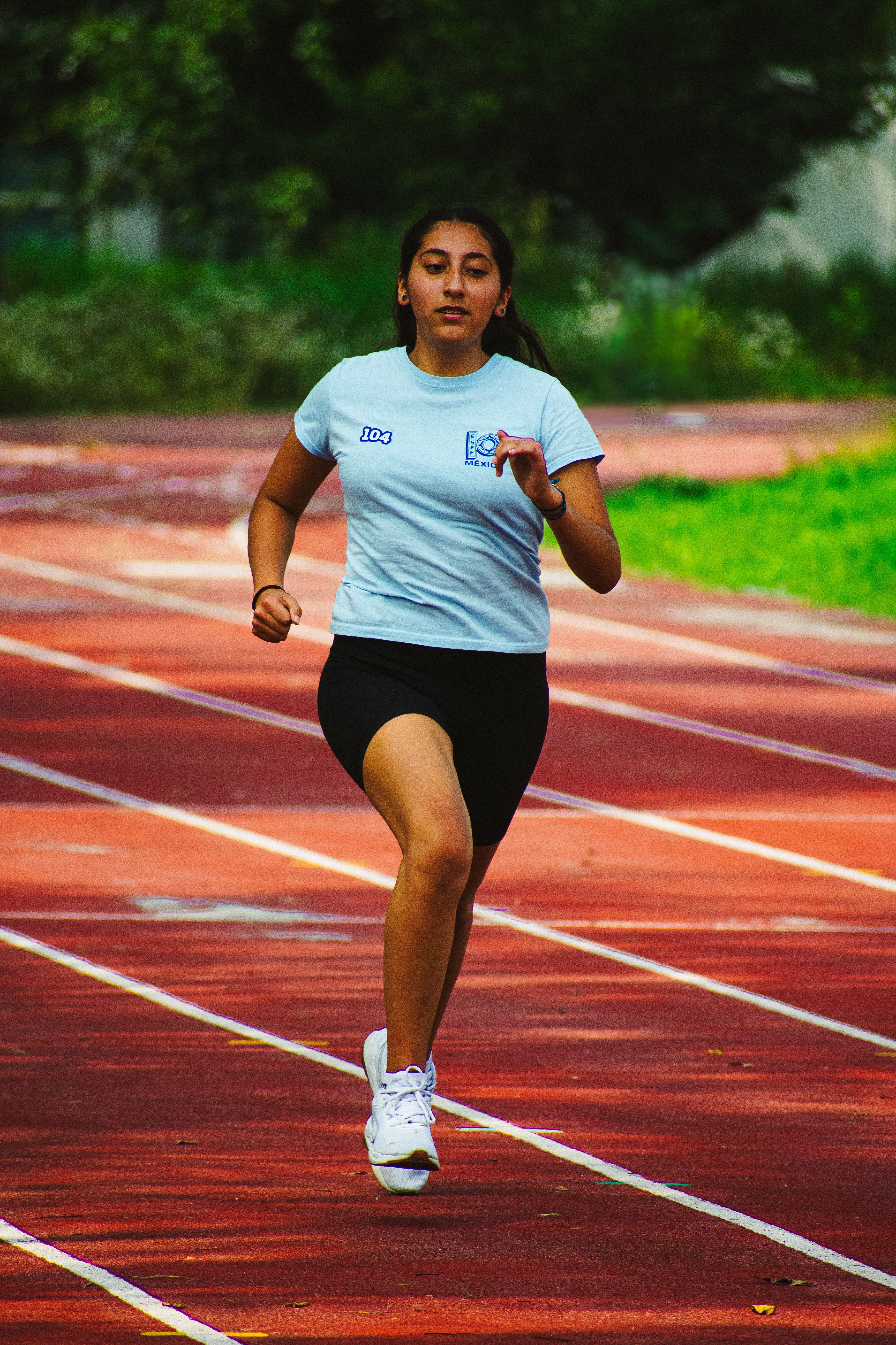 A young woman running on a track outdoors in Ciudad de México, México, showcasing athletic determination.