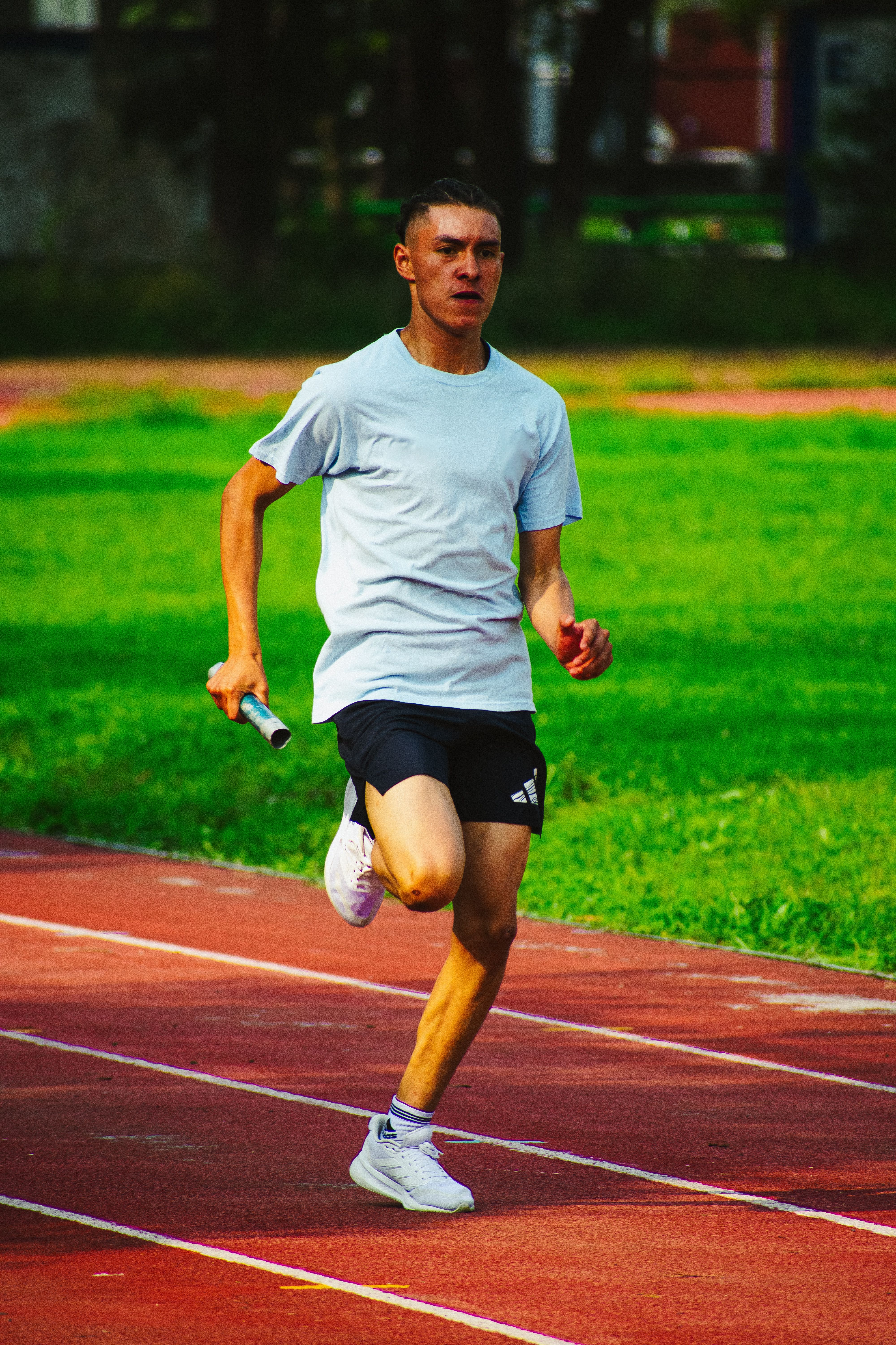 A young male athlete running relay on a track in Mexico City, displaying speed and determination.
