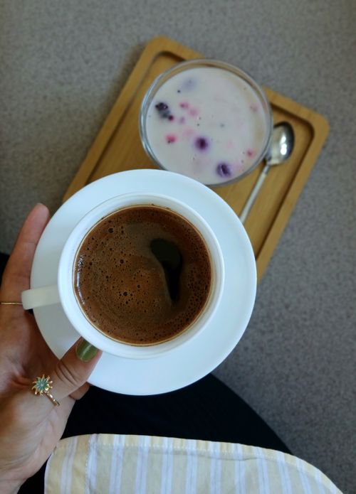 Free Top view of a hand holding a coffee cup with a dessert on a wooden tray. Ideal for brunch themes. Stock Photo