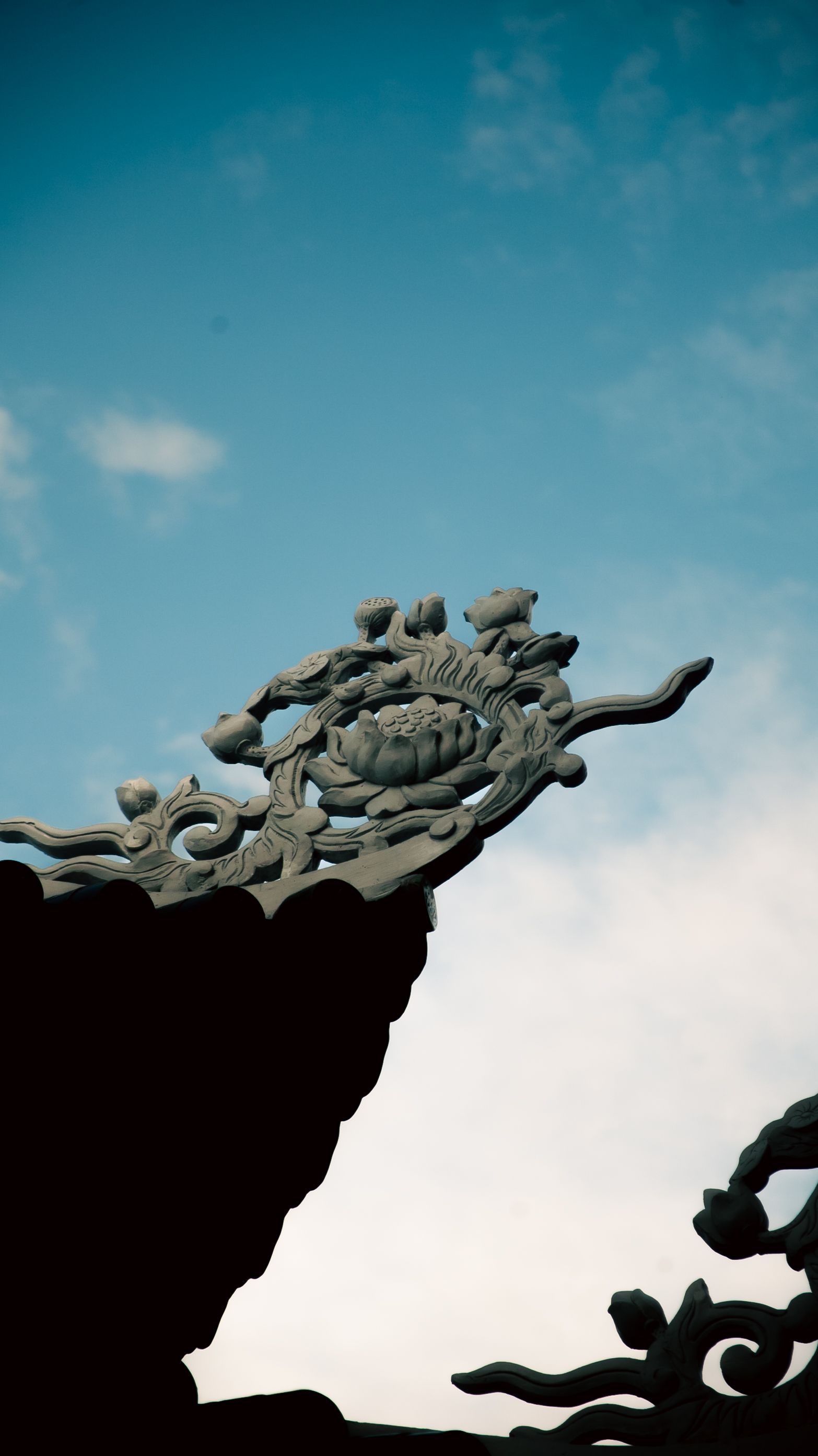 Detailed view of traditional Vietnamese architectural ornament set against a clear blue sky.