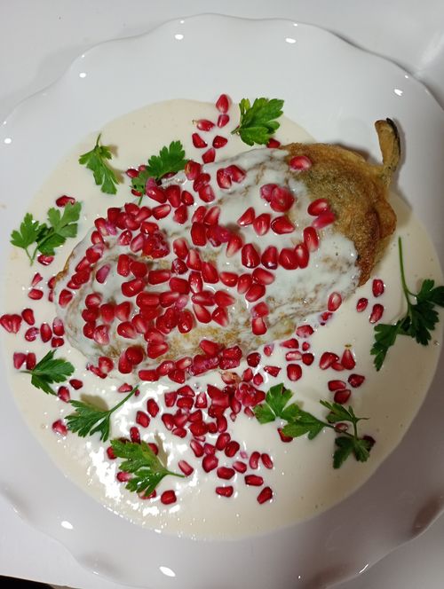 Free Delicious Chile en Nogada garnished with pomegranate and parsley on a white plate. Stock Photo