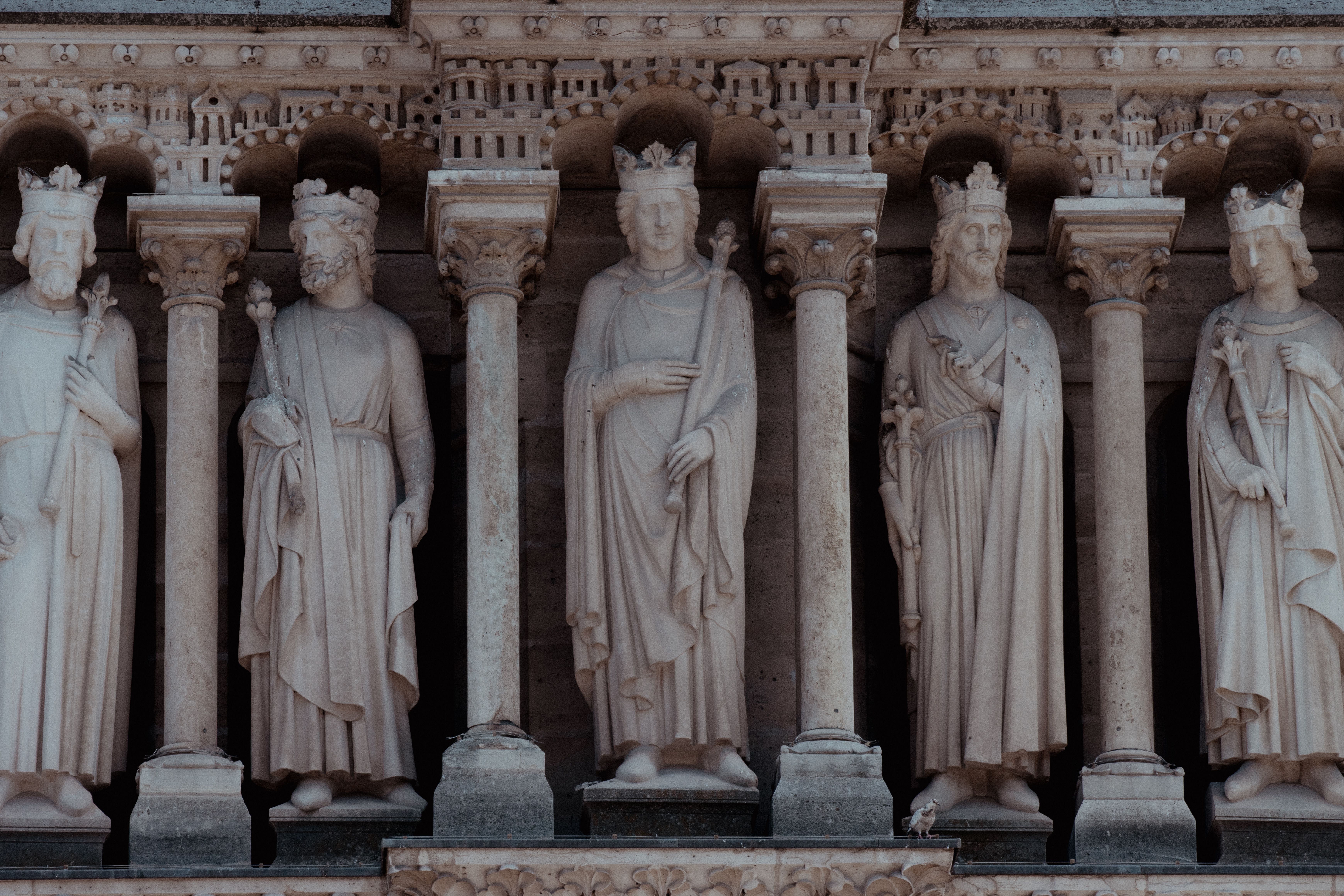 Close-up of stone statues depicting historical figures on the facade of Notre Dame Cathedral, Paris.