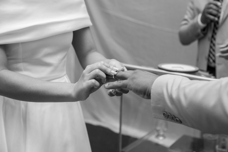 A graceful black and white photo capturing the heartfelt exchange of rings during a wedding ceremony.