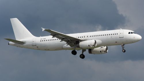 Free White commercial airliner in flight against a dramatic cloudy backdrop. Stock Photo