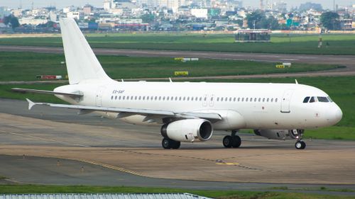 Free Commercial airplane taxiing on runway at airport with cityscape in background. Stock Photo