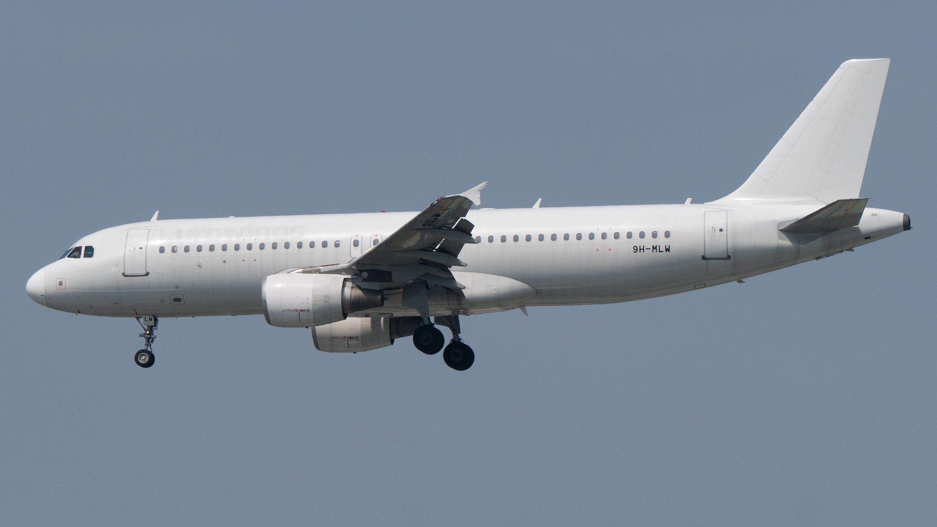 A commercial passenger airplane flying against a clear blue sky.