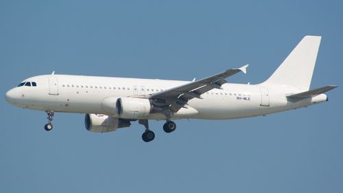 Free White commercial airplane flying under a clear blue sky. Stock Photo