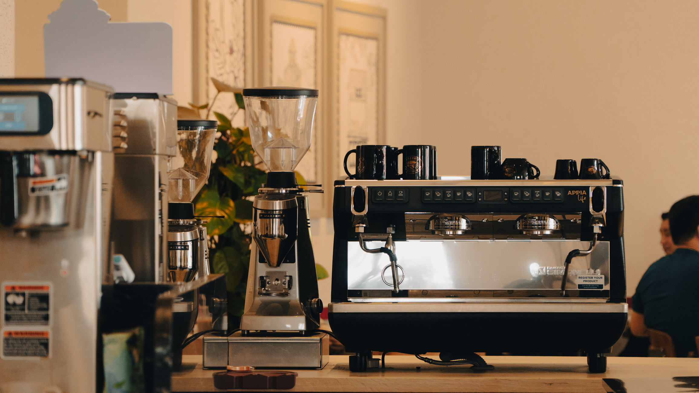 Cozy coffee shop interior featuring a professional espresso machine and grinders.
