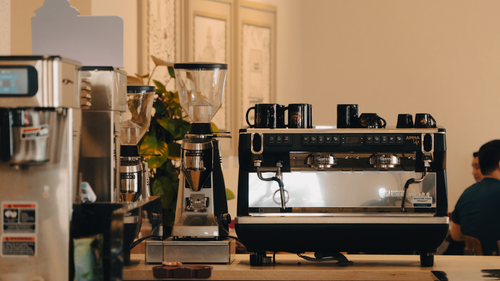 Free Cozy coffee shop interior featuring a professional espresso machine and grinders. Stock Photo