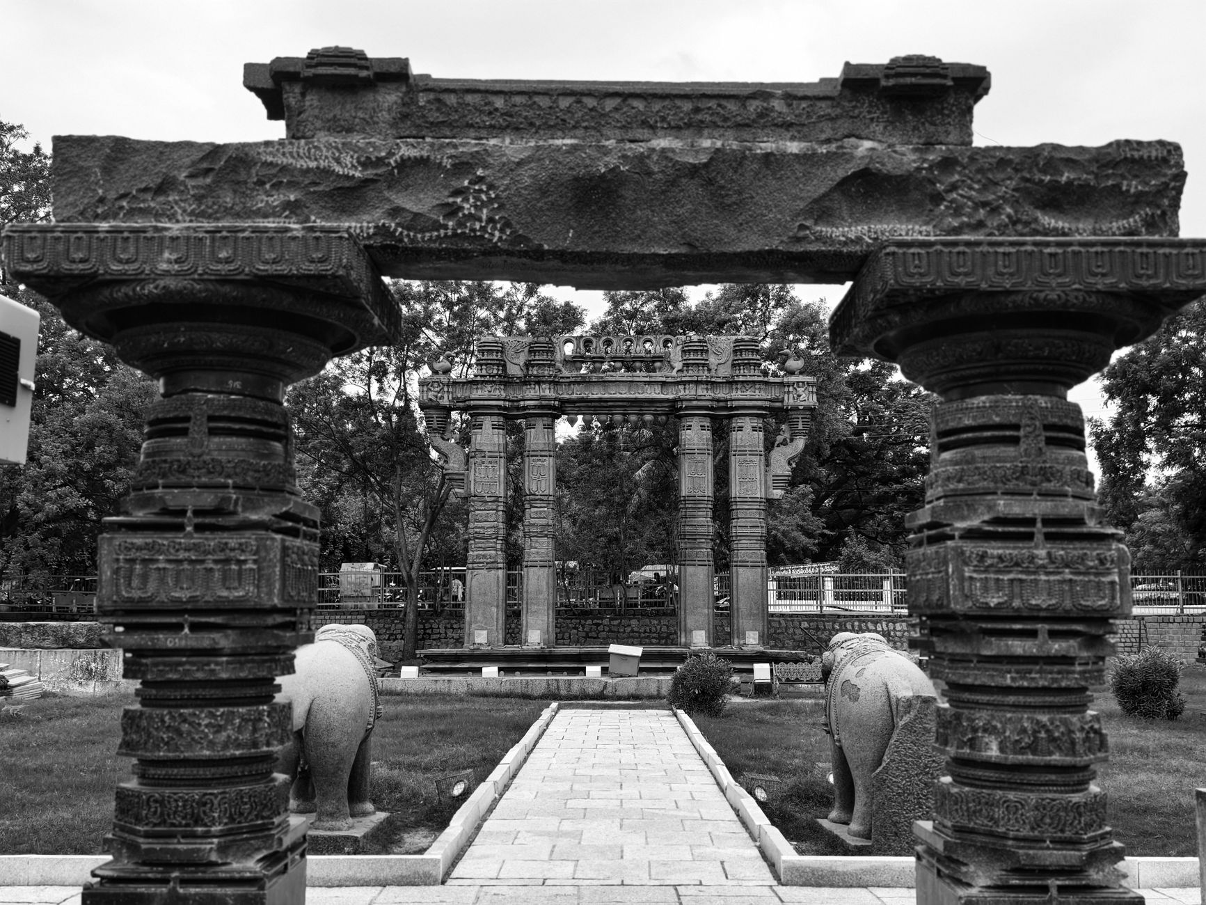 Black and white photo of an ornate stone archway in ancient Indian ruins.