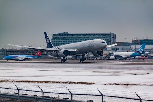 Aircraft flying over runway near airport building