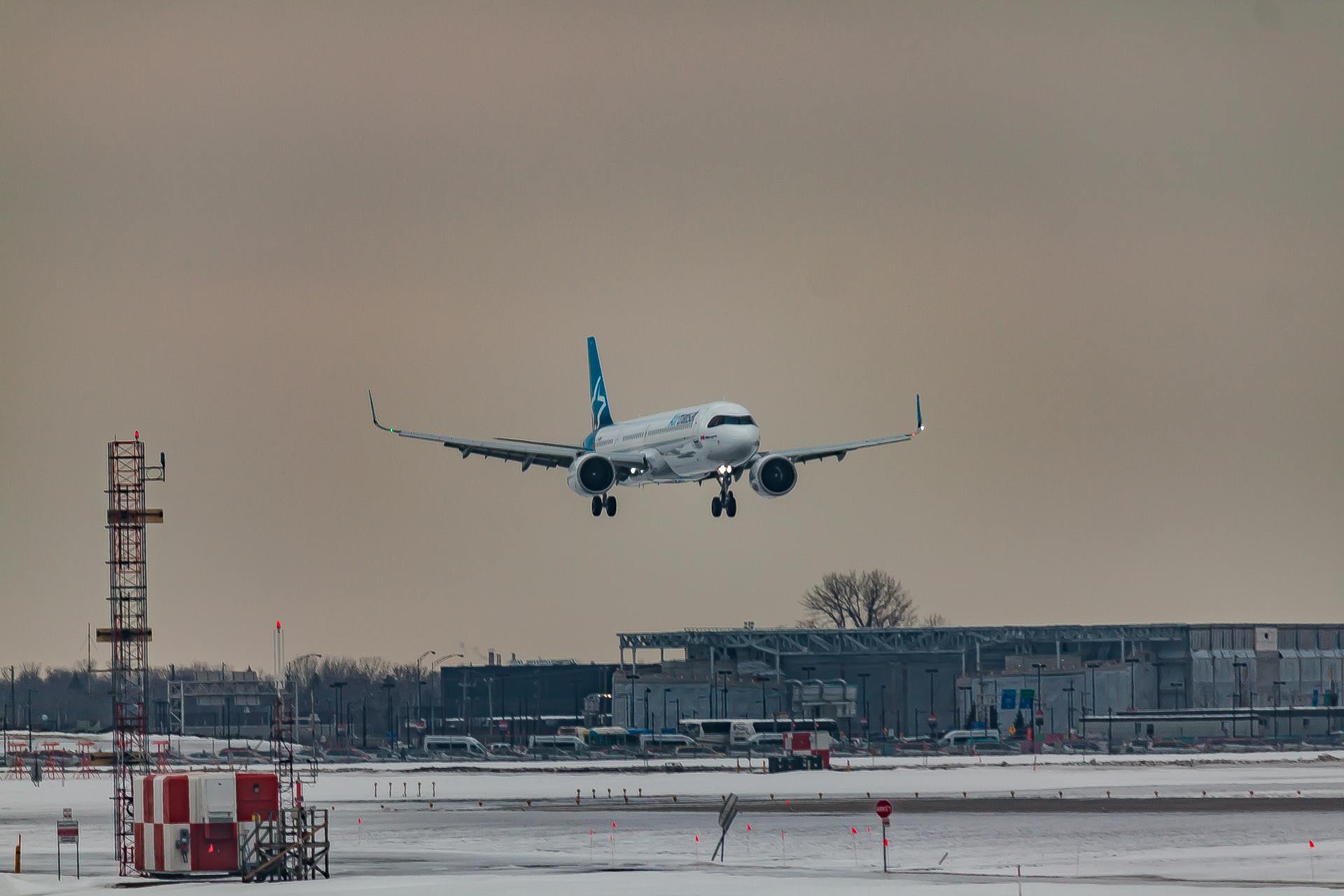 Powerful airplane flying over snowy terrain and preparing for landing on aerodrome airfield against cloudy sunset sky