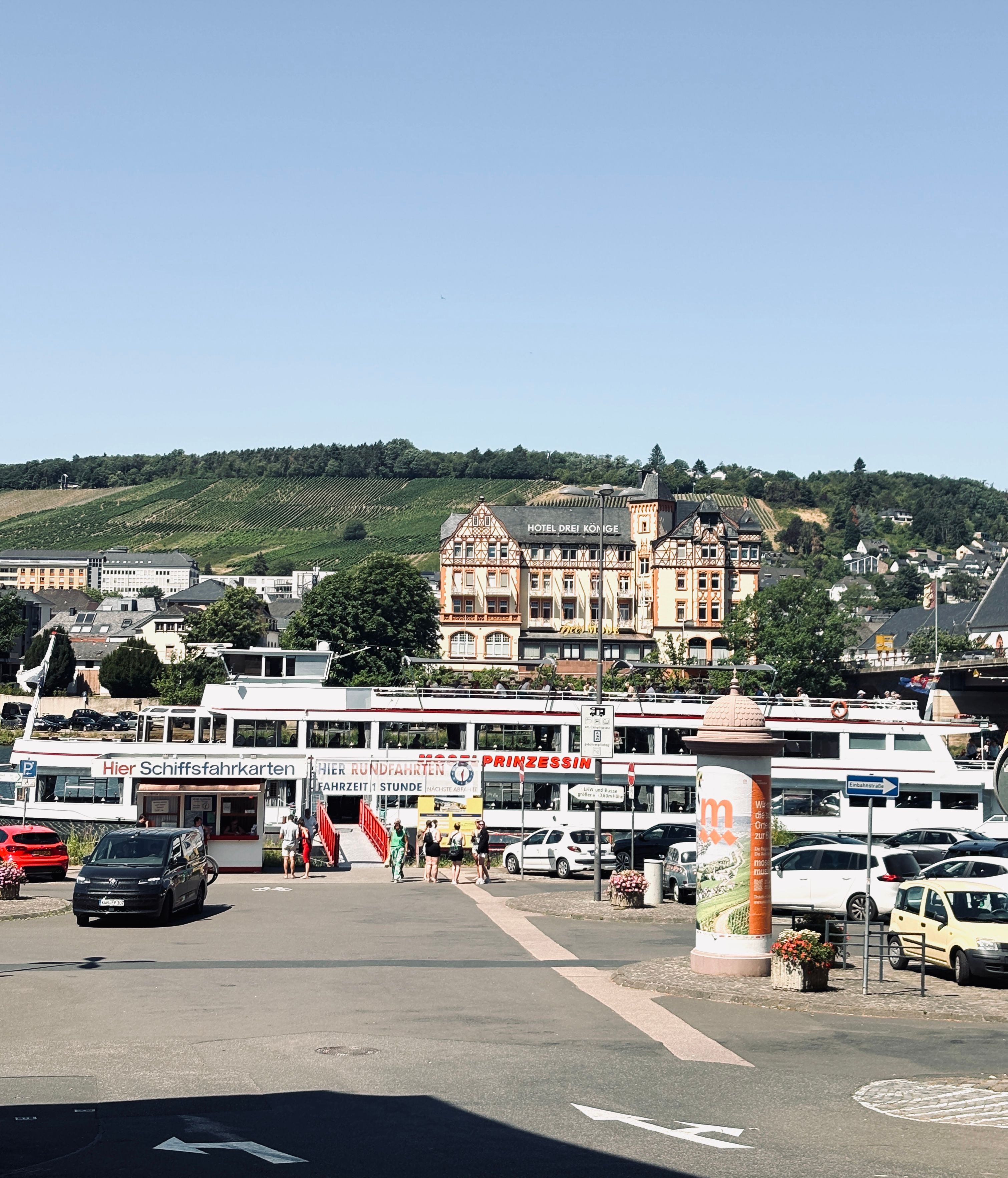 Charming harbor scene in Bernkastel-Kues, Germany featuring boats, classic architecture, and lush vineyards.