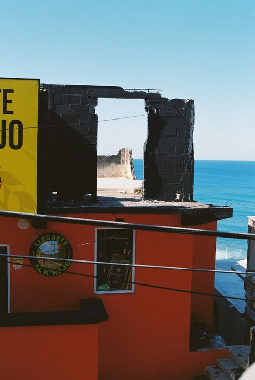 Free Brightly colored building along a coastline with an ocean view through a ruin. Stock Photo