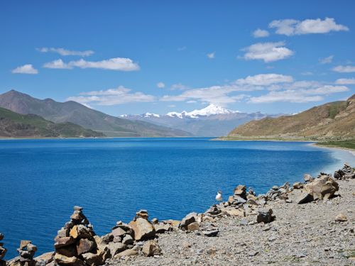 Free A breathtaking view of Yamdrok Lake with snow-capped mountains under a bright blue sky. Stock Photo