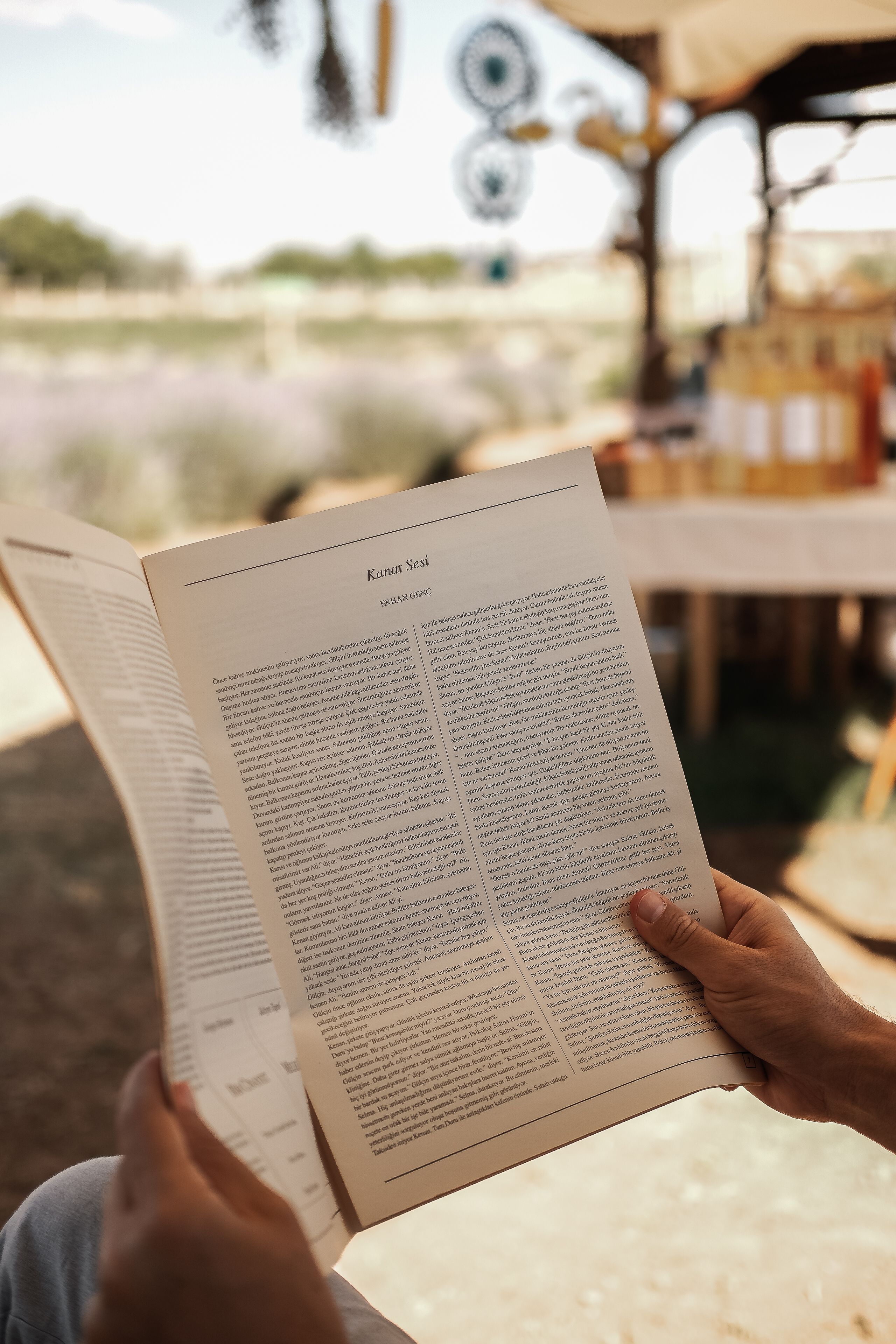 Close-up of a person reading a newspaper under a rustic outdoor canopy.