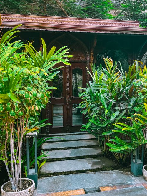 Free A beautiful wooden door surrounded by tropical plants in a serene outdoor setting in Karachi, Pakistan. Stock Photo