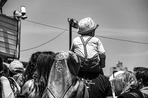 Free Black and white photo of a child on shoulders in a crowded outdoor setting. Stock Photo