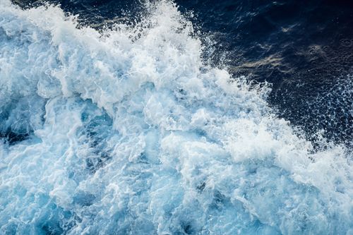Free Aerial view of ocean waves crashing with white foam, creating a vibrant and dynamic seascape. Stock Photo