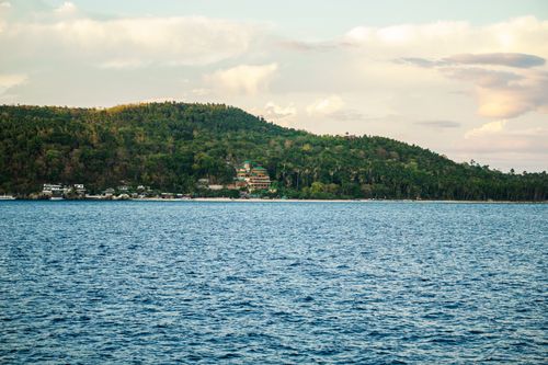 Free A beautiful coastal landscape featuring lush green hills and a serene ocean under a partly cloudy sky. Stock Photo