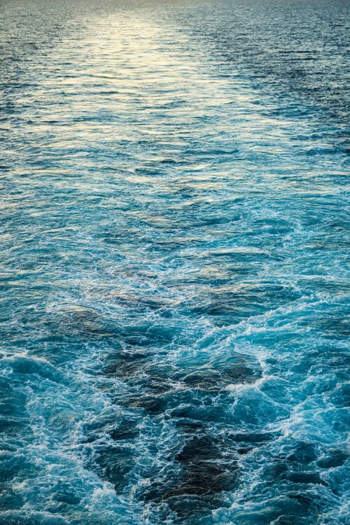 Free Vibrant blue ocean waves captured during a tranquil sunset, showcasing nature's beauty. Stock Photo