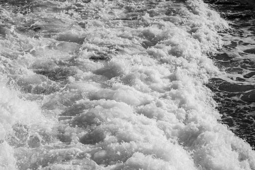 Vivid black and white capture of ocean waves crashing, showcasing natural texture and movement.