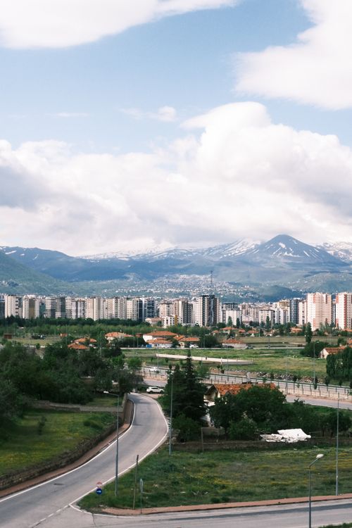 Free Panoramic view of city skyline with snowy mountains under a beautiful blue sky. Stock Photo