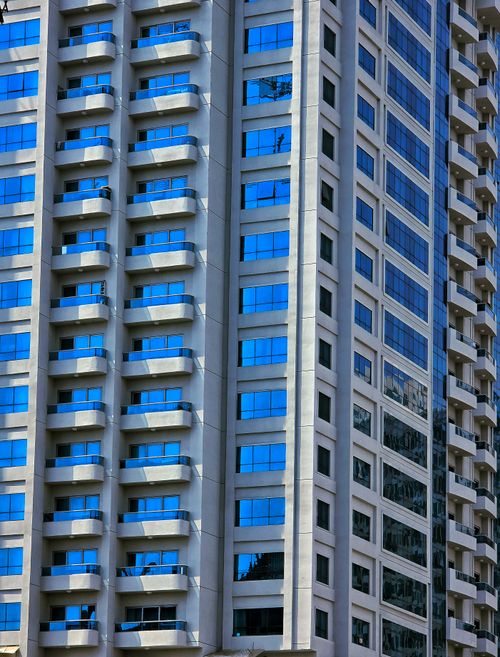 Free Close-up of a modern skyscraper facade reflecting blue sky in Sharjah, UAE. Stock Photo