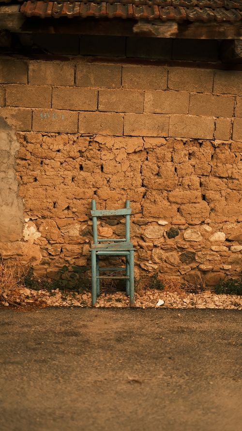 Free A vintage blue chair set against a rustic textured brick wall under warm lighting, ideal for backgrounds. Stock Photo