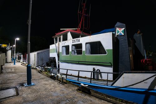 Free Fishing boat docked at a harbor under street lights at night. Stock Photo