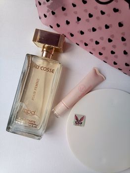 Flat lay of perfume, lipstick, and accessories with a stylish pouch.