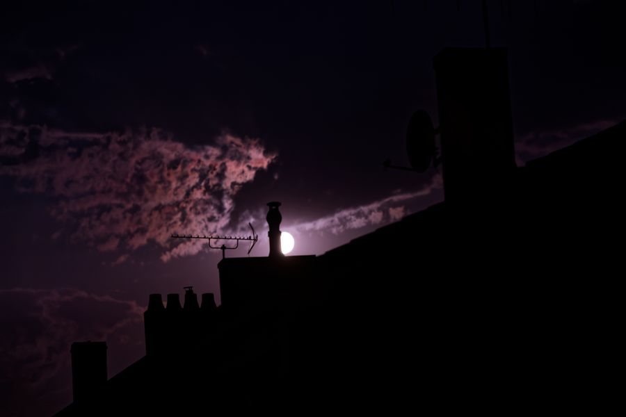 Pleine lune se levant derrière des cheminées, ciel nocturne violet