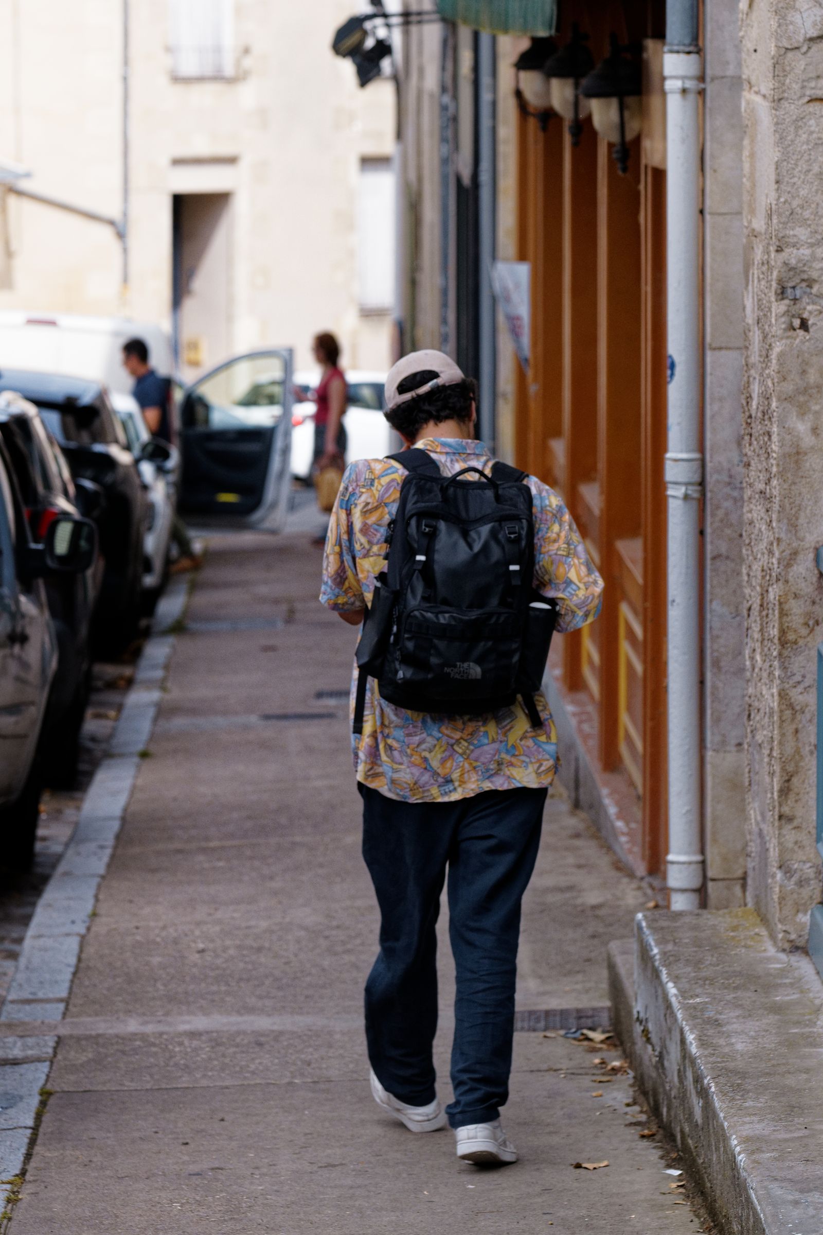 Un homme avec un sac à dos marche dans une ruelle étroite d'un village français