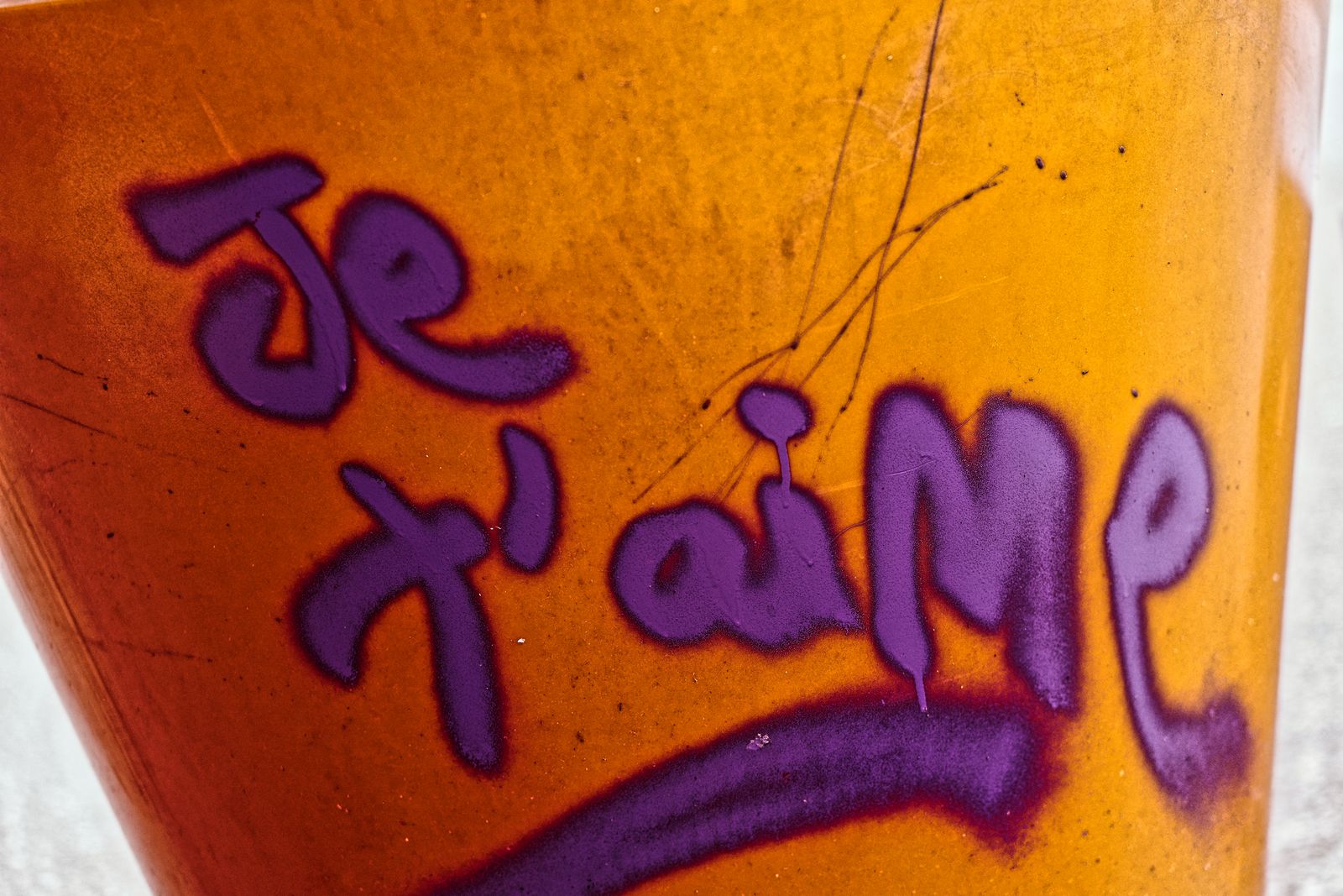 Graffiti « je t'aime » peint en violet sur une surface orangée et rouillée