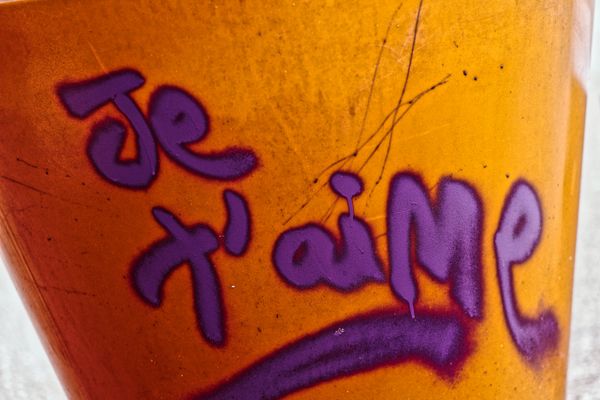 Graffiti « je t'aime » peint en violet sur une surface orangée et rouillée