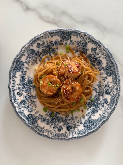 Free Appetizing noodle dish topped with shrimp and sesame seeds on a decorative plate. Stock Photo