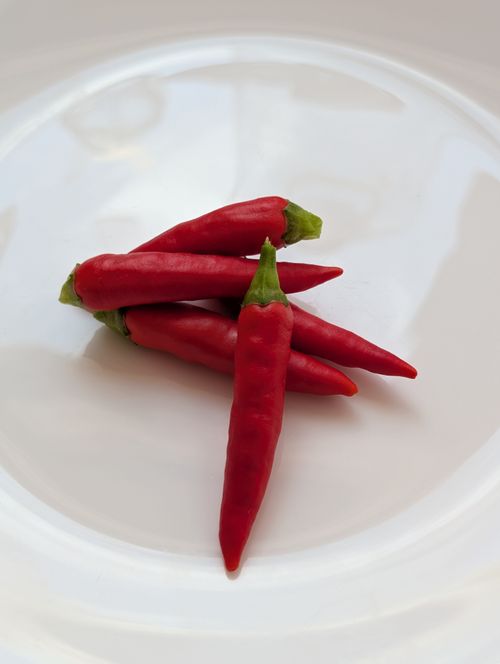 Free Vibrant red chili peppers arranged on a white plate for culinary concept. Stock Photo