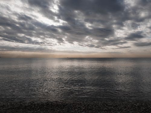 Free Serene evening ocean view with dramatic clouds reflecting on the calm water. Stock Photo