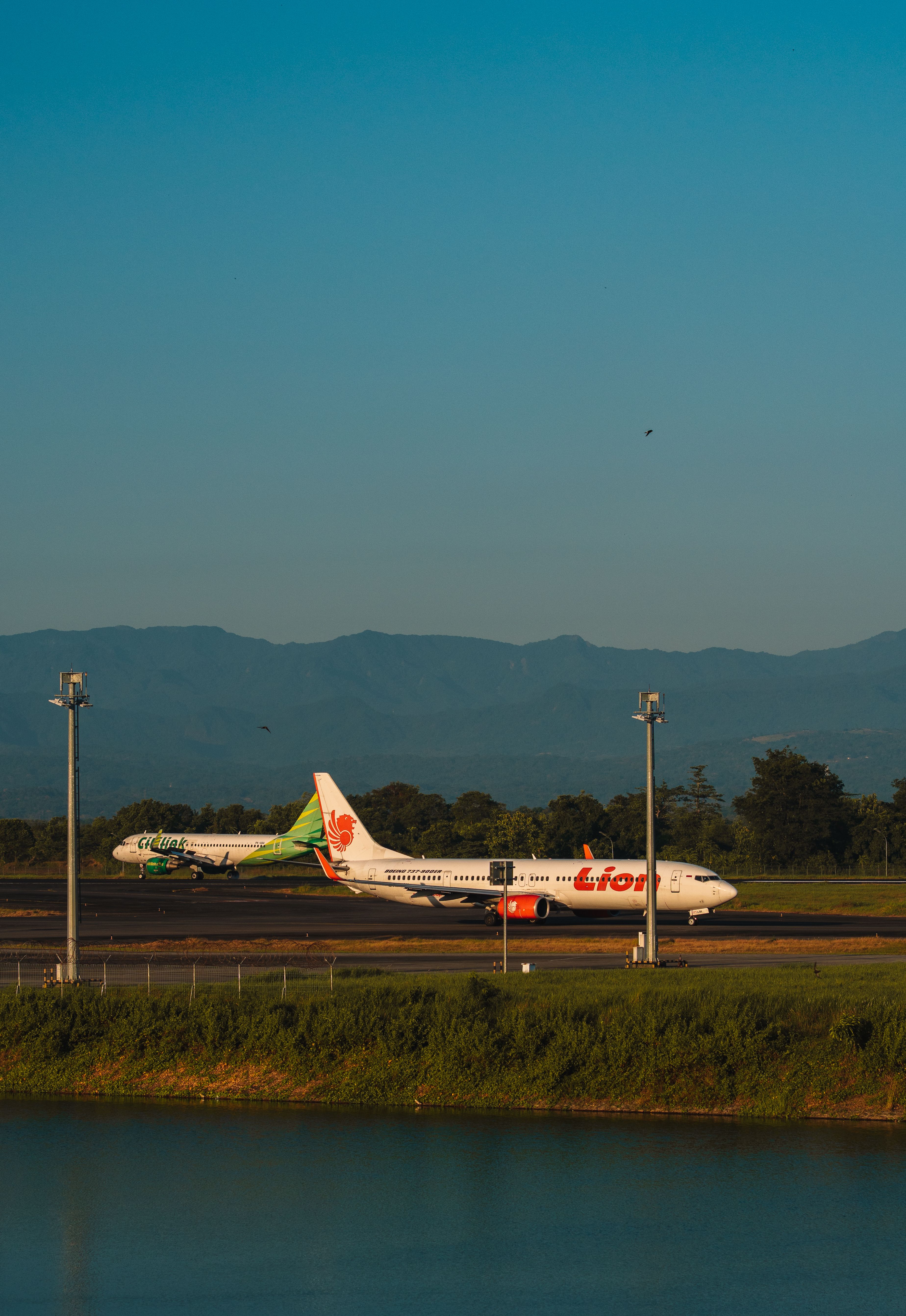 A commercial airplane travels on the runway amid scenic mountains in South Sulawesi, Indonesia.