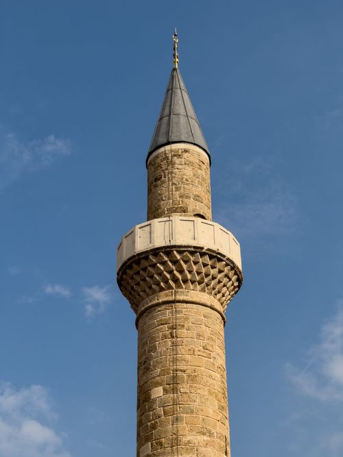 Free Stone minaret tower of an Ottoman-style mosque with a clear blue sky backdrop. Stock Photo