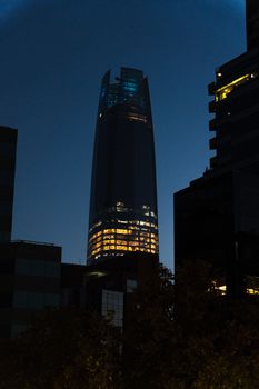 Gran Torre Santiago illuminated at dusk, showcasing urban skyline of Santiago, Chile.