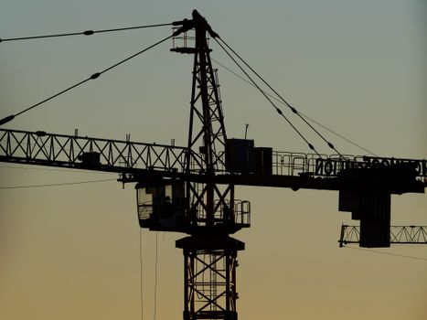 Silhouette of a construction crane against a colorful sunset sky, symbolizing urban development.