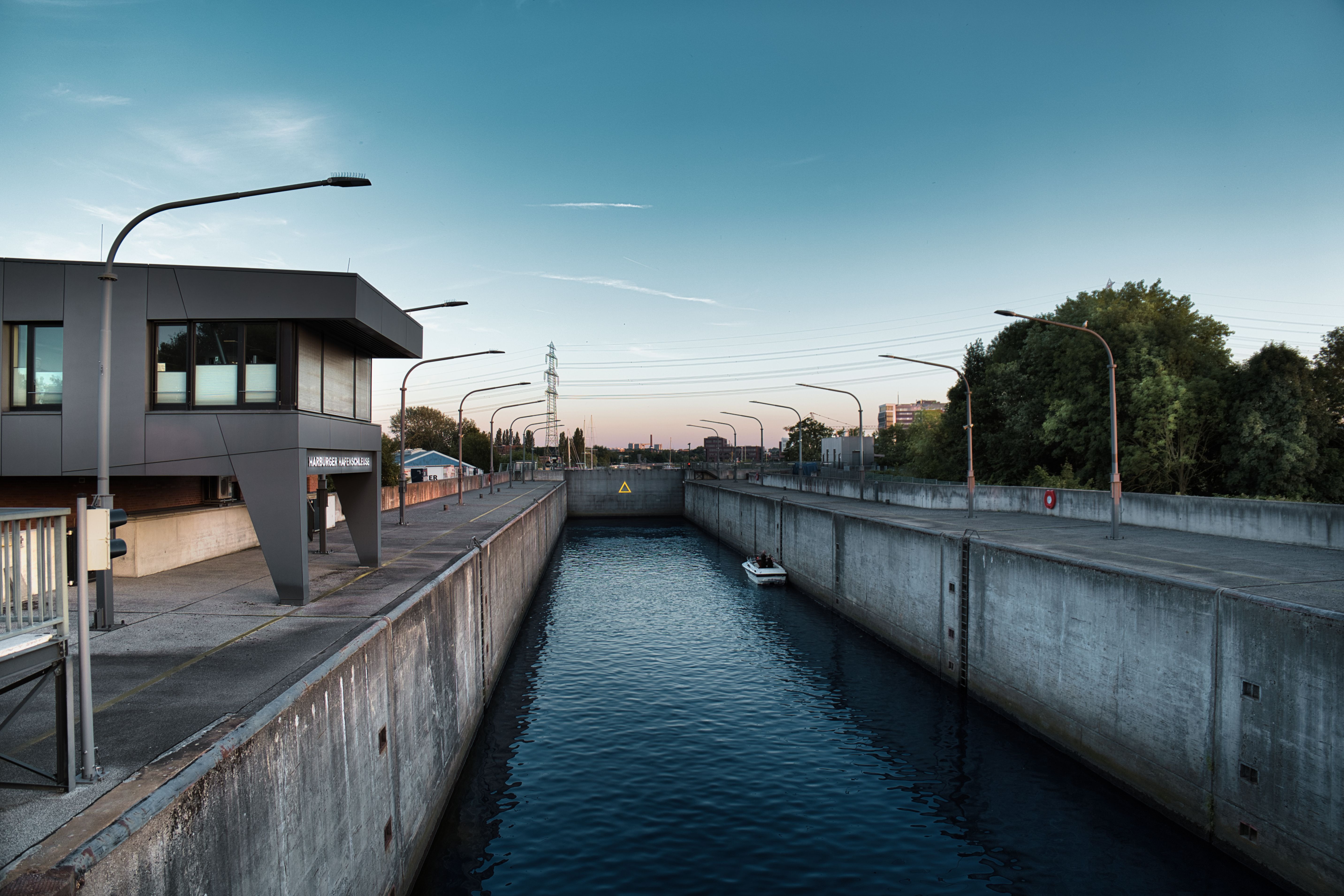A stylish concrete canal lock with a small boat at dusk, perfect for marine and architecture visuals.