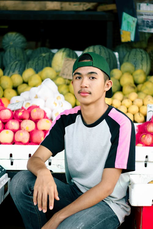 Free Boy In Crew Neck T-shirt And Green Cap Beside Fruit Stand Stock Photo