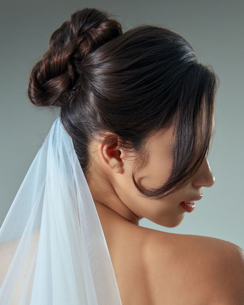 An intricate bridal updo under a veil